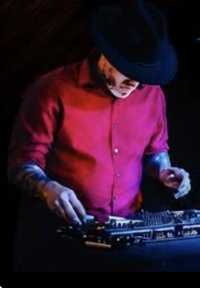 DJ Zach B at his mixing equipment wearing a black hat and red shirt